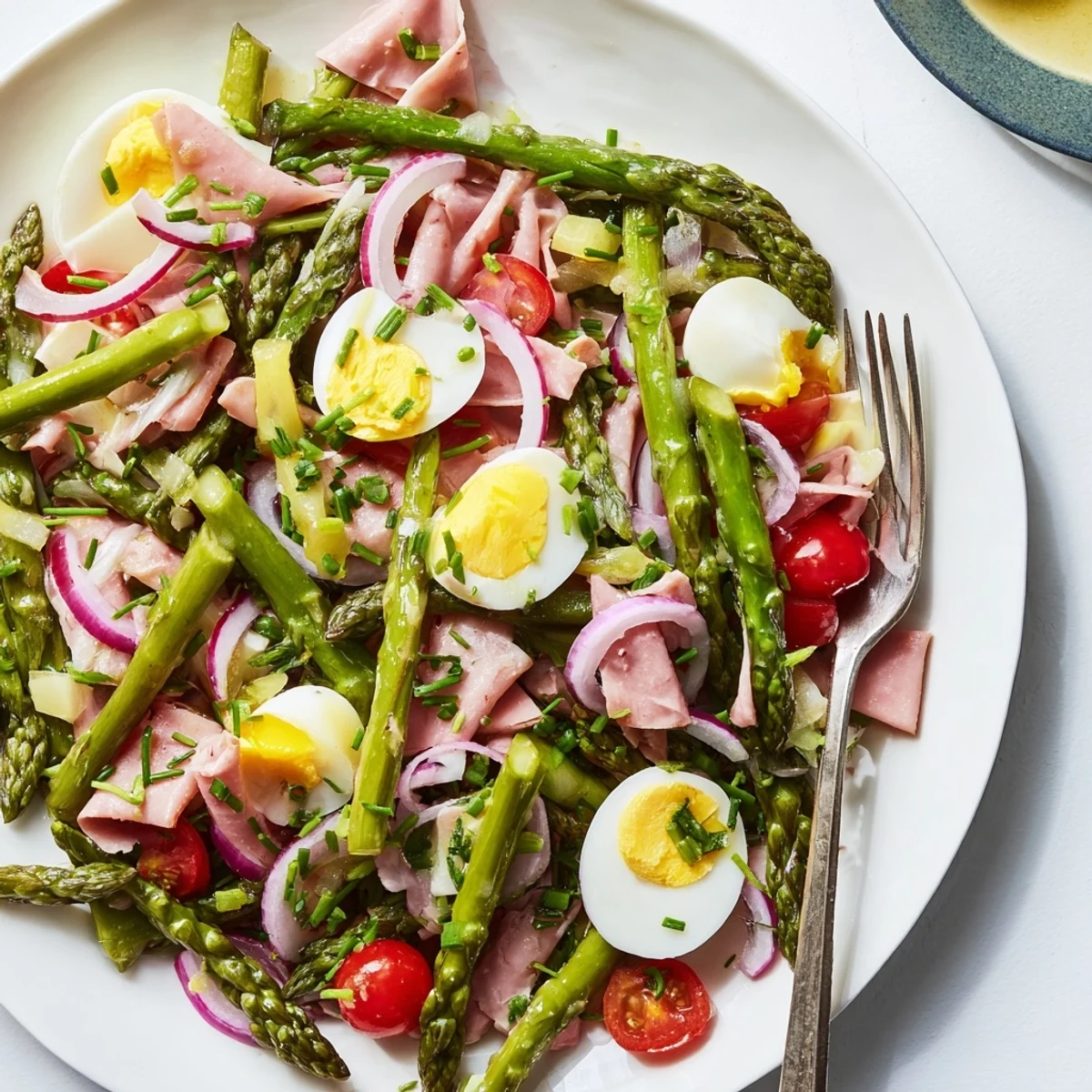 Frischer Spargelsalat mit Schinken und Eiern, serviert mit Dijon-Vinaigrette.  